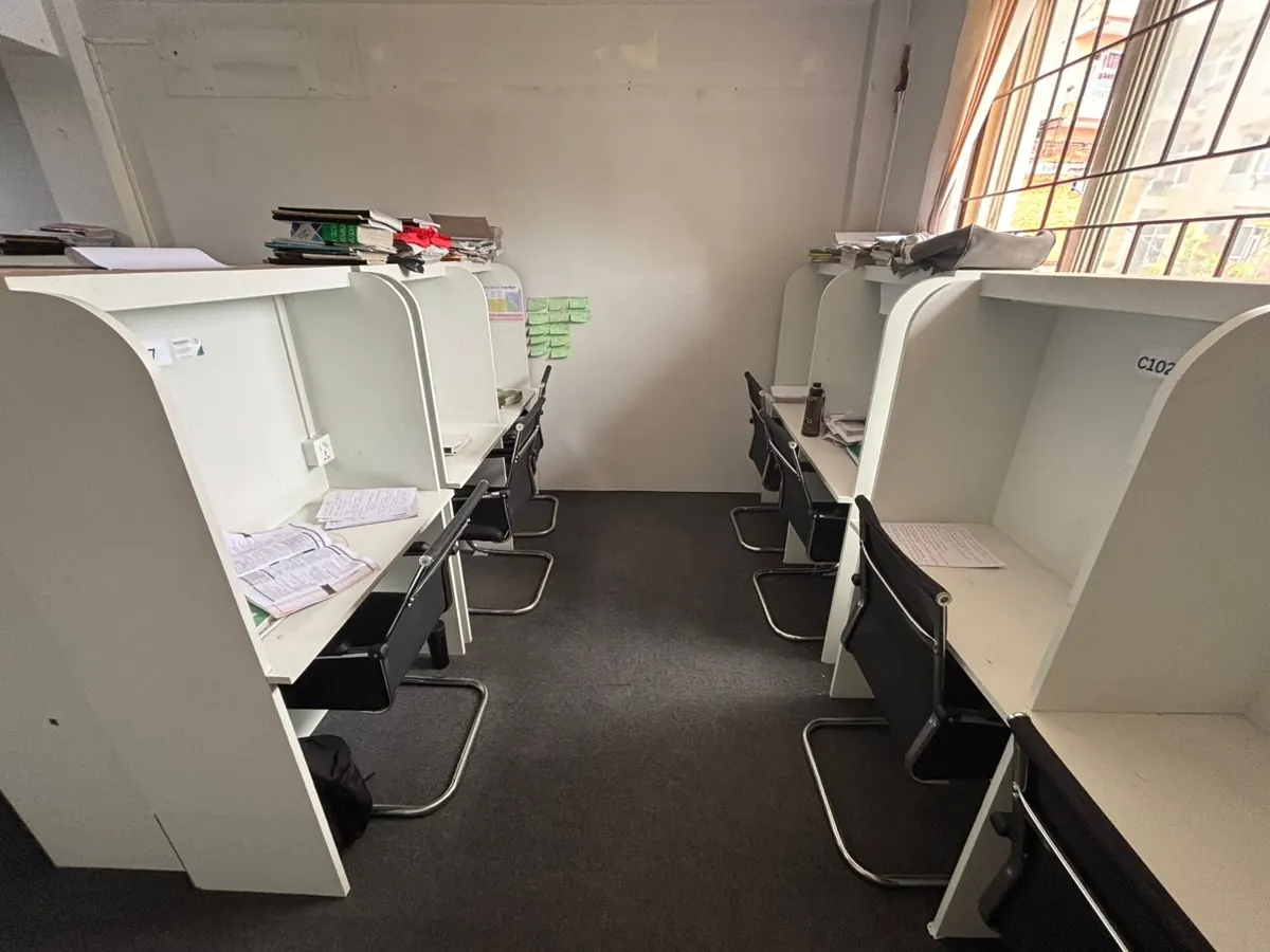 White cabins in a hall with large windows, books and notes on the desks.